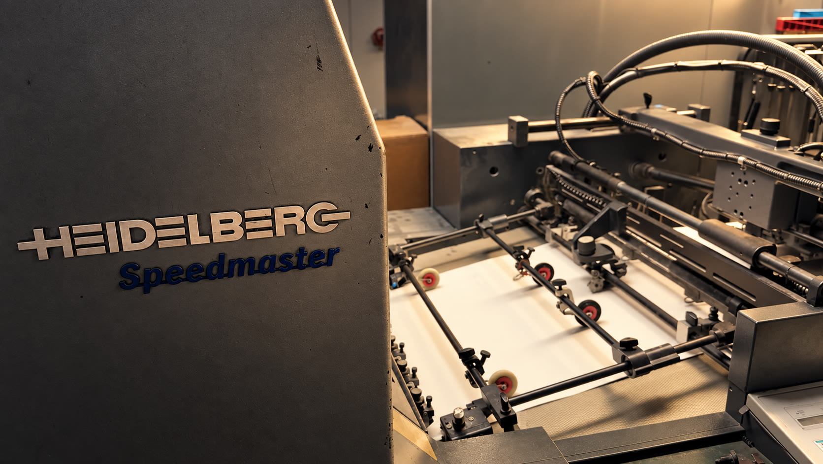 Warm light across the Heidelberg Speedmaster and its paper feed in our Austin shop